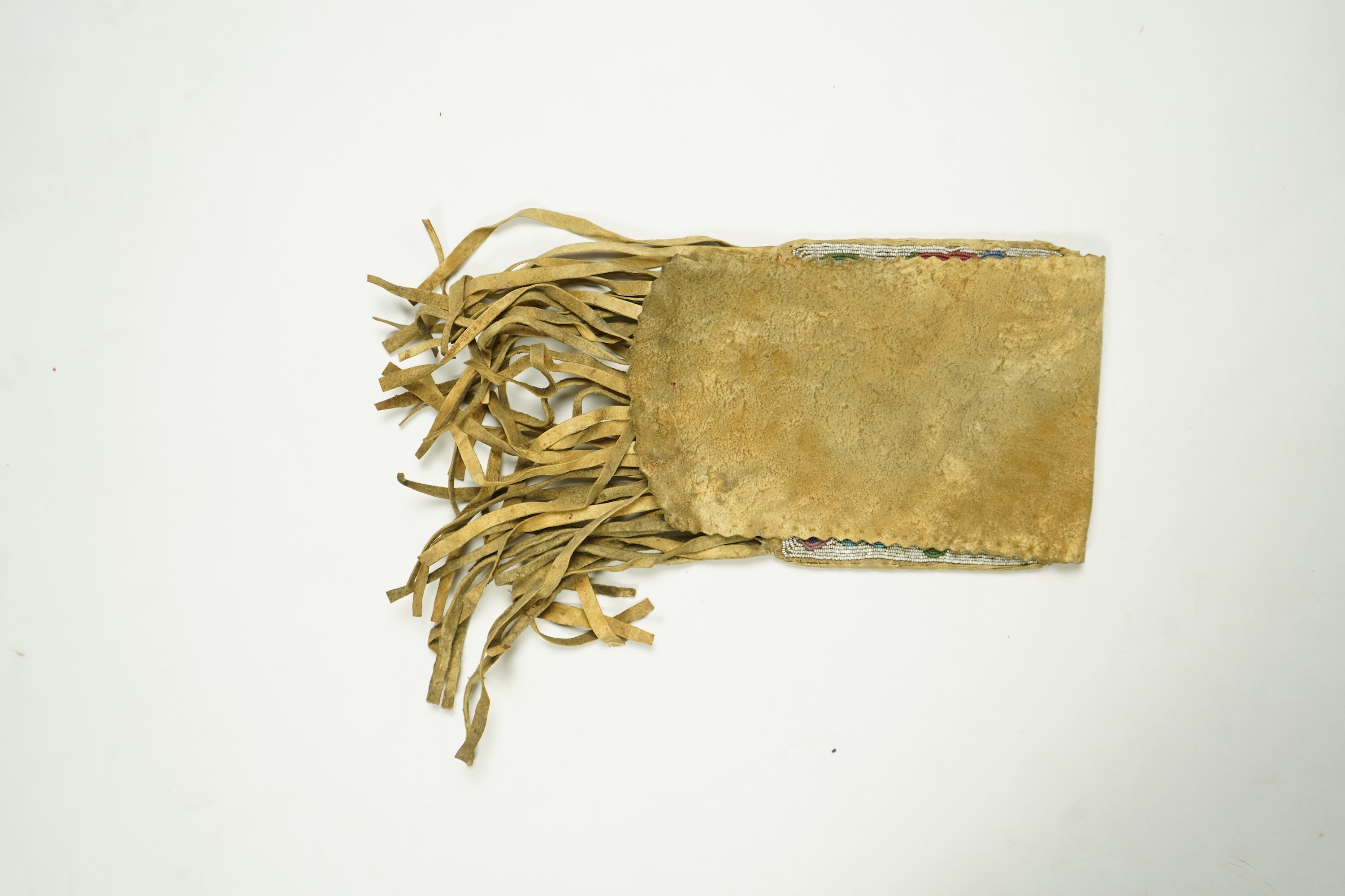 A late 19th century Native American beaded and fringed hide bag. With two different decorative beaded panels front and back. Possibly Cree. 60cm long. Condition - both panels of beadwork are in good condition. The hide a